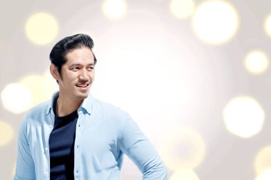 Mavi gömlek ayakta bokeh karşı olan yakışıklı Asya adam arka plan ışıklar. Sevgililer günü