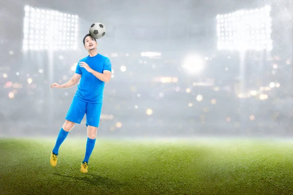 Attractive asian soccer player in action with the ball in stadium background