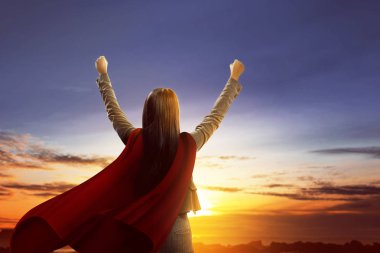 Arkadan Görünüş Süper iş kadının günbatımı arka plan üzerinde kırmızı pelerin konumu olan