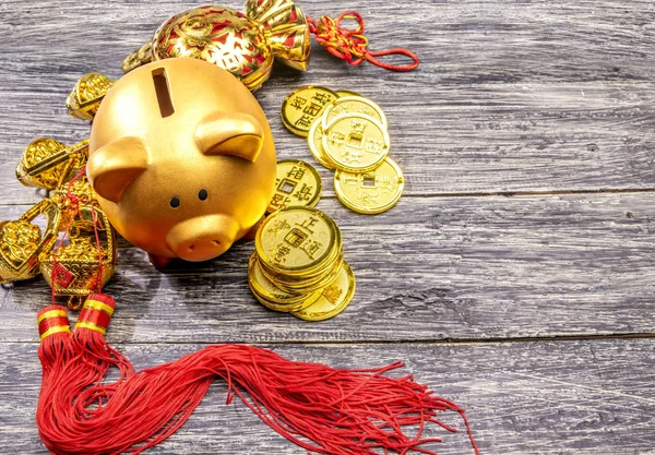 Altın sikke ve ahşap masa üzerinde Çince süslemeleri ile Piggy banka. 