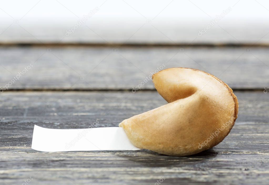 Fortune cookie with blank paper on wooden table