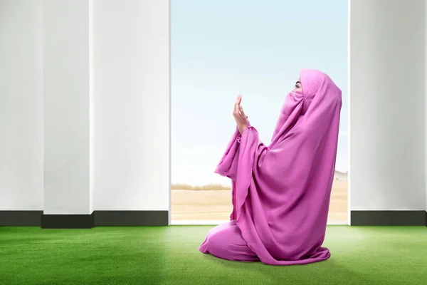 ピンク色で美しいアジア女性祈りの位置に座っているベールで覆われ 背景に青い空とドアを開けて部屋の中のカーペットの上手を上げる — ストック写真
