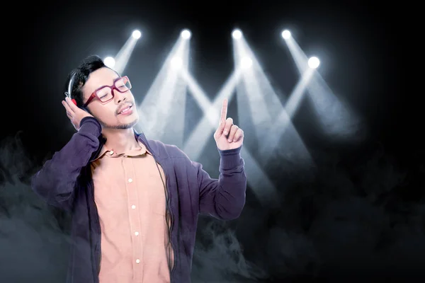 Happy asian man in glasses wearing brown jacket listen the music — Stock Photo, Image