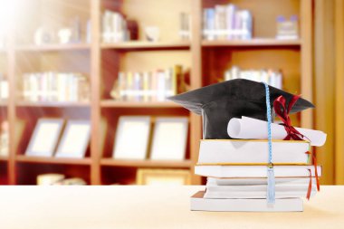 Mezuniyet şapka, diploma kaydırma ve masanın üzerine kitaplar kitaplar