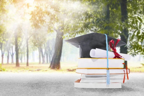 Cappello di laurea, pergamena diploma e libri sul lato strada con t — Foto Stock