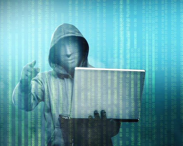 Хакер в чорний балахон Холдинг ноутбук з його боку, вказуючи — стокове фото