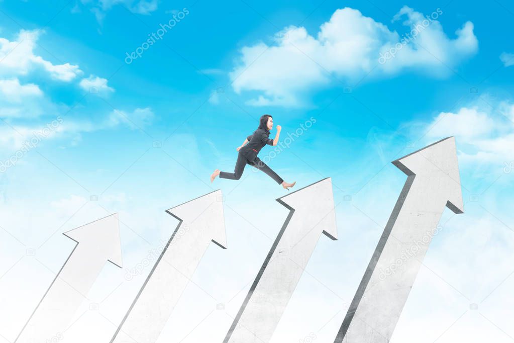 Happy asian business woman jumping above white arrows