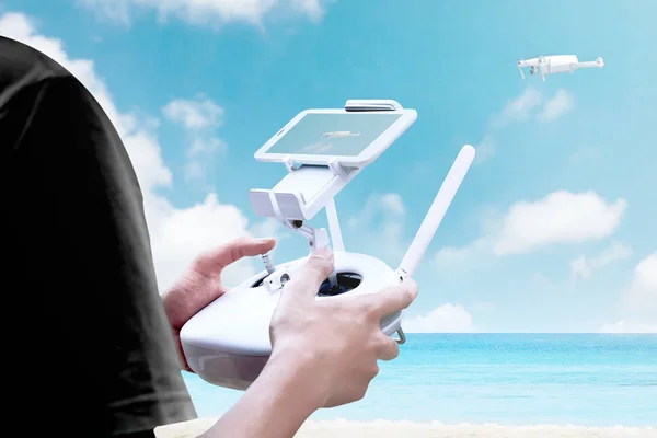 Bageste billede af mand kontrollerende hvid drone, der flyver over b - Stock-foto