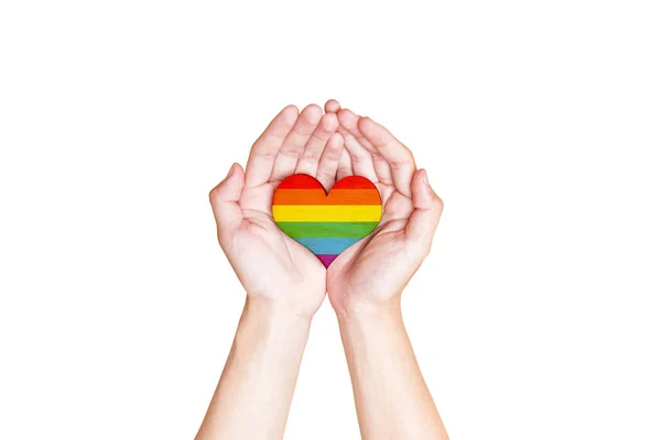 Ludzkie ręce trzymanie serca z tęczową flagą jako symbol LGBT — Zdjęcie stockowe