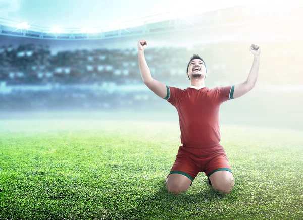 El jugador de fútbol celebra su gol con los brazos y la rodilla levantados —  Fotos de Stock