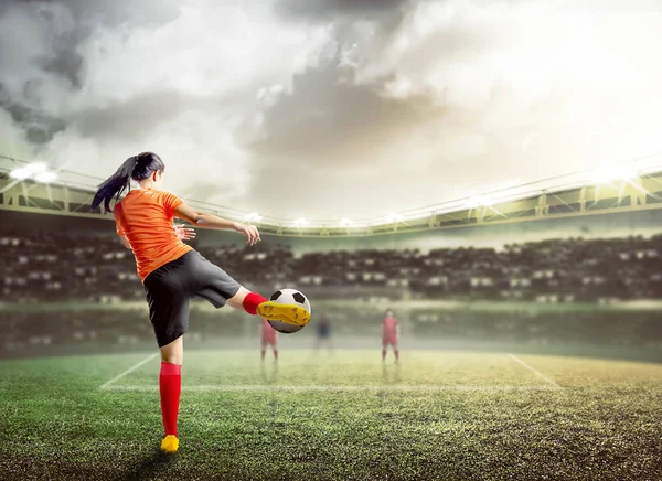 Vista trasera de mujer futbolista asiática en jersey naranja kickin —  Fotos de Stock