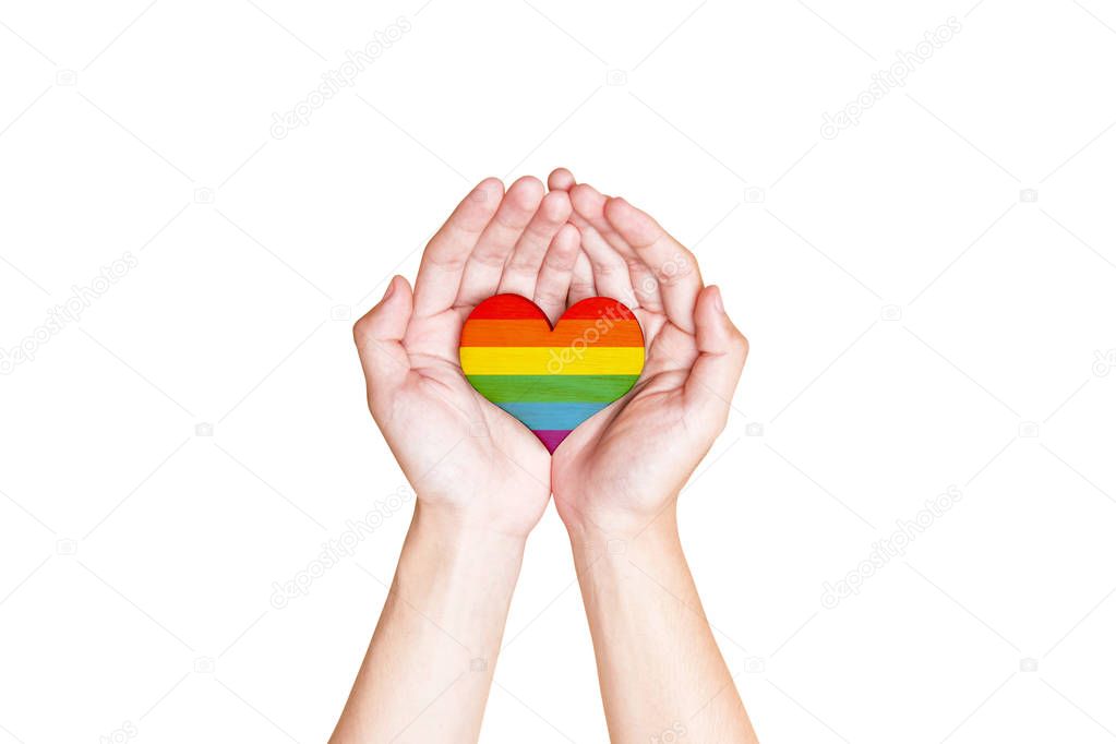 Human hands holding heart with rainbow flag as a symbol of LGBT