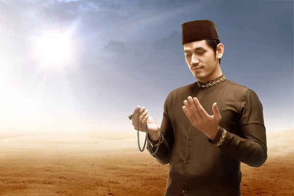 Asijský muslimský muž stojící a modlící se, zatímco pozvedl paže s pra — Stock fotografie
