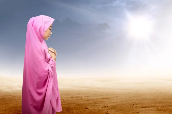 Asian muslim woman in veil praying on desert — Stock Photo, Image