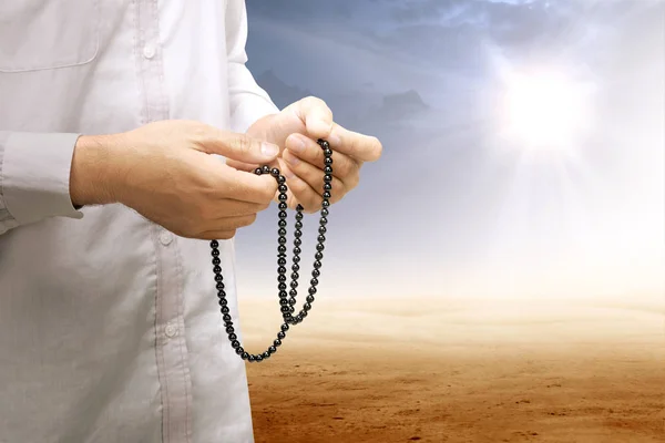 Muslim man praying with prayer beads on his hands on desert — Stock Photo, Image