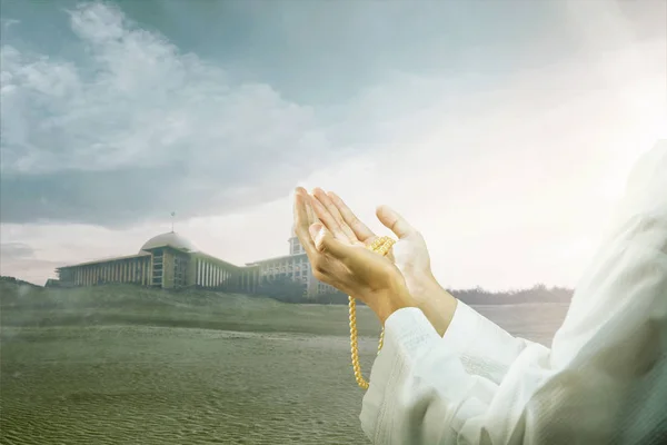 Muslim man praying with prayer beads on his hands on the sand du — Stock Photo, Image