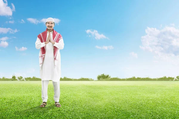 Asian muslim man in cap praying on the green grass field — Stock Photo, Image