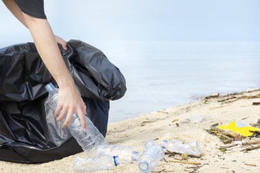 Çöp torbası olan el adam sahilde plastik şişe toplayarak