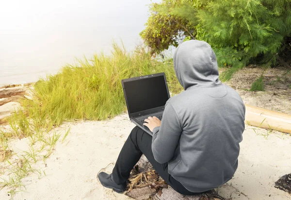 Rückansicht eines Mannes in schwarzem Kapuzenpulli mit Laptop — Stockfoto