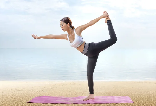 Asiatico donna sana praticare yoga sul tappeto in spiaggia — Foto Stock