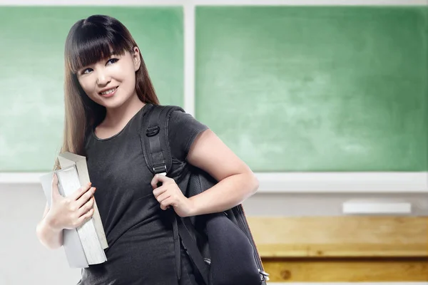 Asiática estudante mulher com mochila carregando livro na sala de aula — Fotografia de Stock