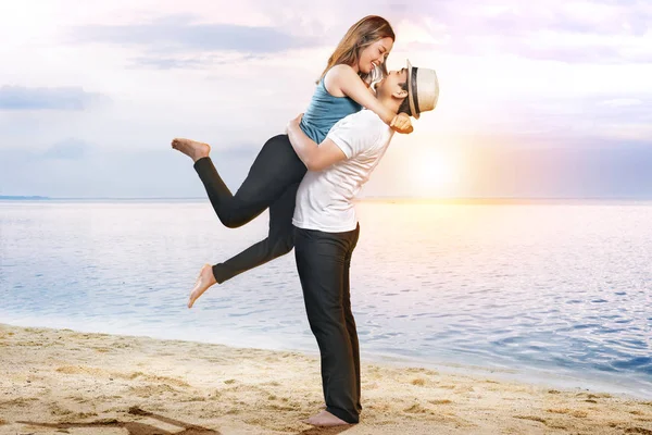 Glücklich asiatische Mann in Hut umarmt seine Freundin am Strand — Stockfoto