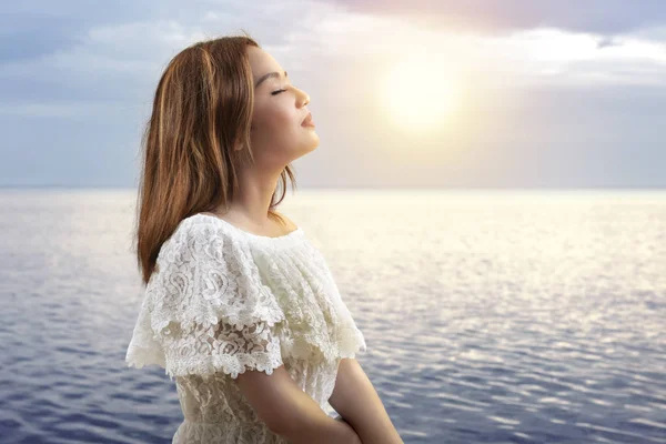 Asiatique fille en tenue blanche se détendre et profiter du coucher de soleil sur la — Photo