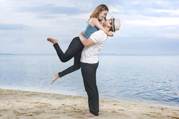 ビーチで彼のガールフレンドを抱きしめる帽子で幸せなアジアの男 — ストック写真