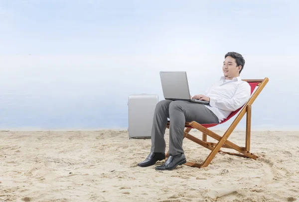 Empresário asiático trabalhando com laptop sentado na cadeira de praia — Fotografia de Stock