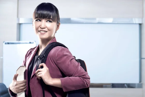 Asiática estudiante mujer con mochila llevar libro de pie y loo —  Fotos de Stock