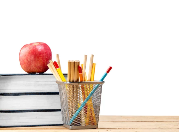 Pile of books with apple and pencils in basket container on wood — Stock Photo, Image