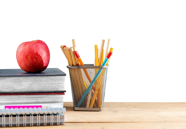 Pile of books with apple and pencils in basket container on wood — Stock Photo, Image