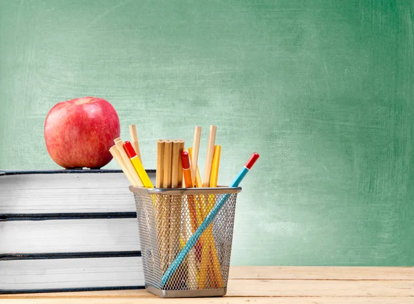 Tumpukan buku dengan apel dan pensil dalam wadah keranjang di atas kayu — Stok Foto