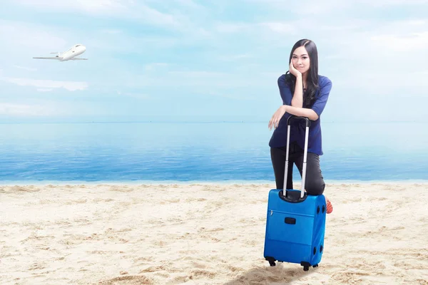 Mujer asiática con maleta de pie en la playa — Foto de Stock