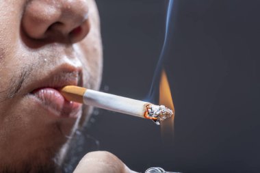 Çakmaklı adam sigara yakıp sigara içiyor.