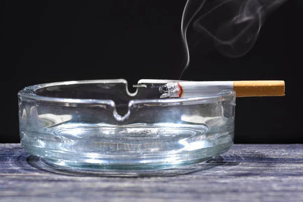 Cigarette on transparent ashtray — Stock Photo, Image