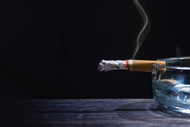 Ahşap masa üzerinde şeffaf kül tablası üzerinde sigara