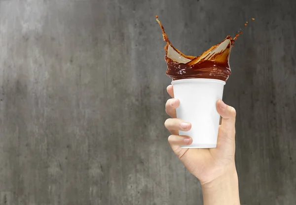 Mão segurando uma xícara de isopor com salpicos de café — Fotografia de Stock