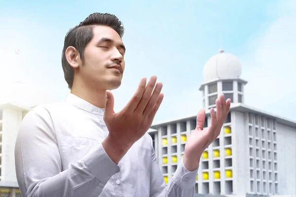 Asian Muslim man standing and praying while raised arms — Stock Photo, Image