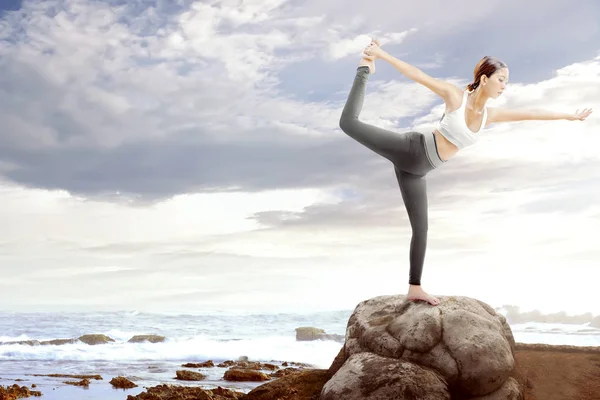 Asiatico donna sana praticare yoga sulla roccia in spiaggia — Foto Stock