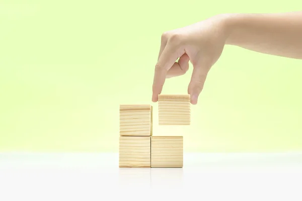 Χέρι χτίσει μια στοίβα από ξύλινο παιχνίδι μπλοκ στο τραπέζι — Φωτογραφία Αρχείου