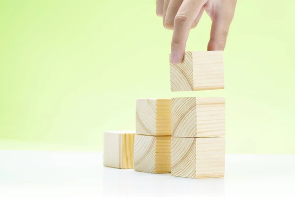 Χέρι χτίσει σκάλες από ξύλινο μπλοκ παιχνίδι στο τραπέζι — Φωτογραφία Αρχείου