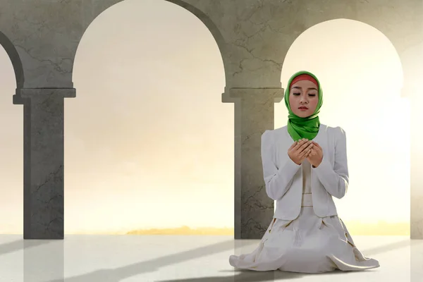 Asian Muslim woman sitting in pray position while raised hands a