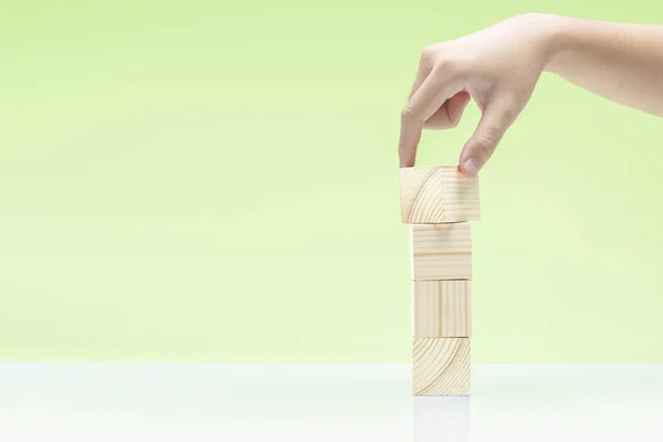 Hand build a stack of wooden block toy on the table — Stock Photo, Image