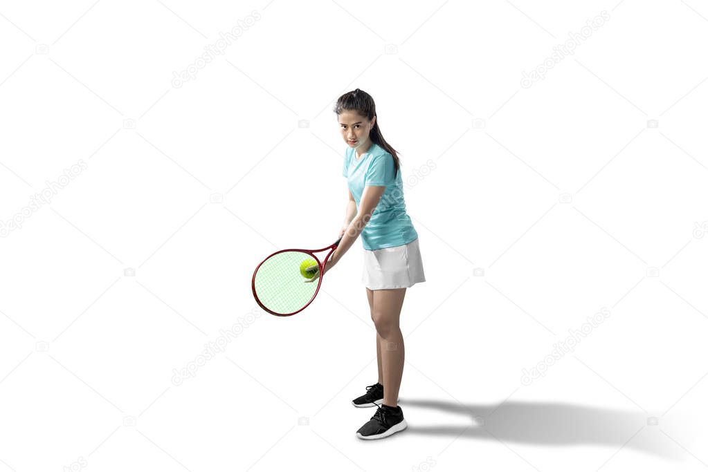 Asian woman with a tennis racket and ball in her hands ready in 