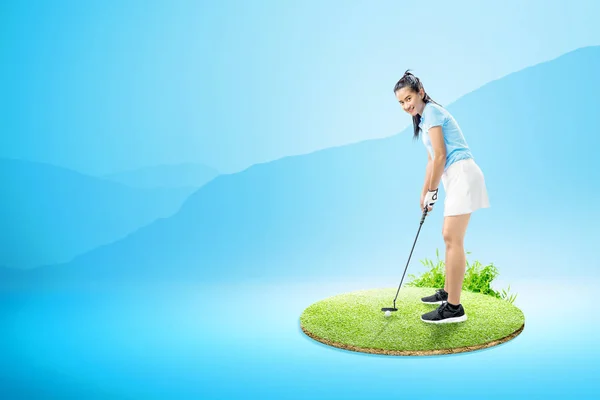 Aziatische vrouw met een putter Golf Club klaar om de bal te raken — Stockfoto