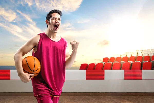 Asiatische Mann Basketballspieler hält den Ball mit einem aufgeregten exp — Stockfoto