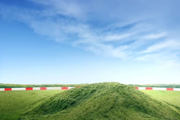 Зелене поле з курганом землі і блакитним небом — стокове фото
