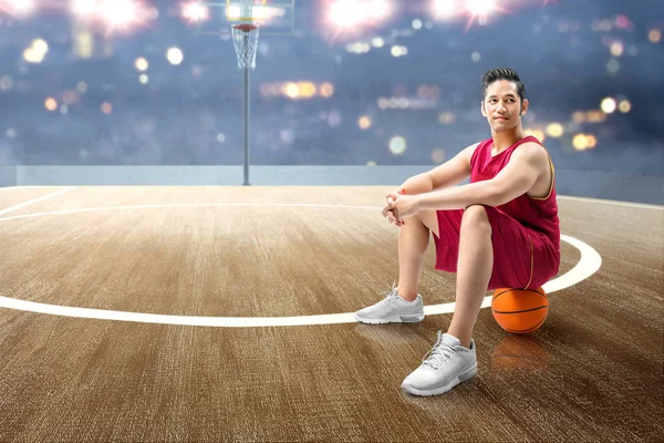 Asiatisk man basketspelare sitter på bollen — Stockfoto