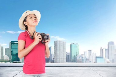 Şapka asyalı kadın cityscape bir resim çekmek için kamera tutan